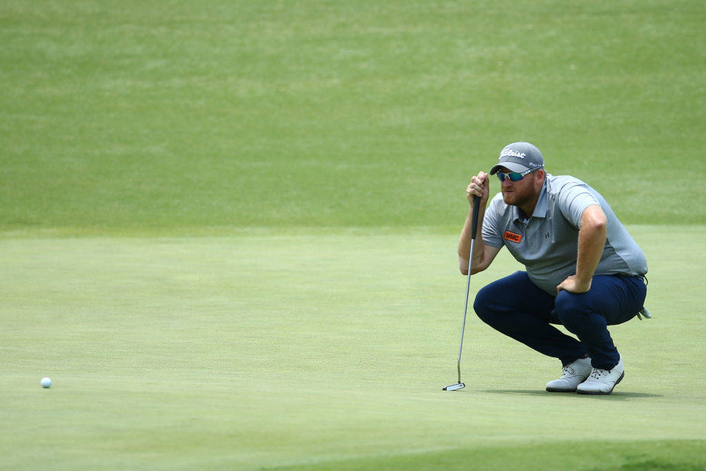 Aaron Pike crouches over a putt